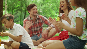 四口家庭幸福时光在树林里野餐吹泡泡25秒视频
