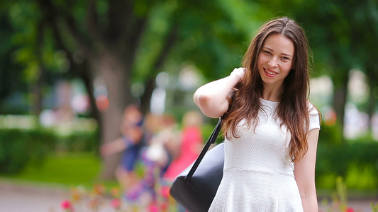 美丽的年轻女士在户外画像在公园中微笑的美丽快乐女人视频