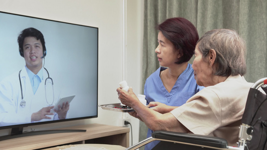 老年妇女坐在家中与医生进行;妇女坐在家里视频