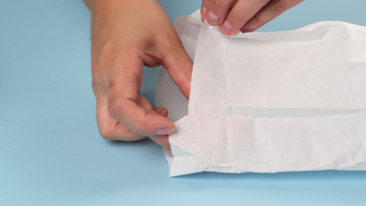 两只手折叠成两只多色烤面纱放在一个白纸袋里视频