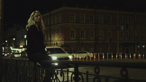 女孩晚上坐在长椅上在城市的灯光下享受市中心的城市生活10秒视频