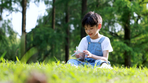 小男孩坐在草地上玩小飞机玩具10秒视频