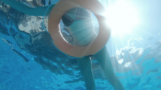 漂亮的女人在泳池里放松带着充气安全环慢动作水下风景视频
