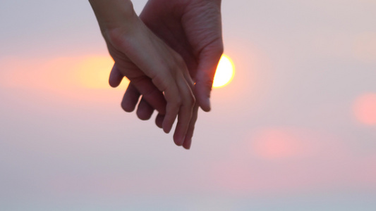 关闭两个恋人手牵手男人和女人手牵着手在日落模糊背景视频