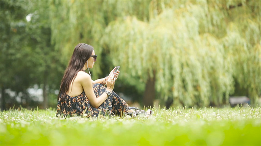 可爱女人坐在公园里时正在看手机短信的短信笑声视频