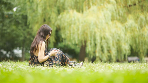 可爱女人坐在公园里时正在看手机短信22秒视频