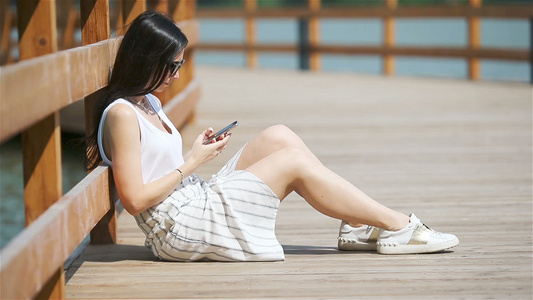 可爱女人坐在公园里时正在看手机短信的短信笑声视频