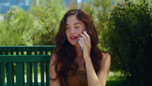 微笑的女孩在公园长椅特写镜头上讲电话13秒视频