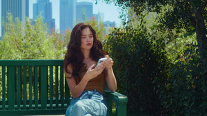 亚洲女孩坐在公园长椅上拿着电话10秒视频