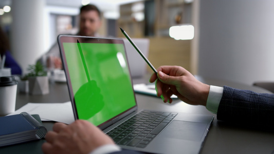 使用笔记本电脑绿屏的商务人士在会议桌上分析公司数据视频