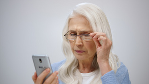老年女性带着老花镜费力地看着手机屏幕9秒视频