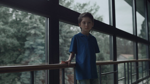 悲伤的男孩独自站在全景窗前18秒视频