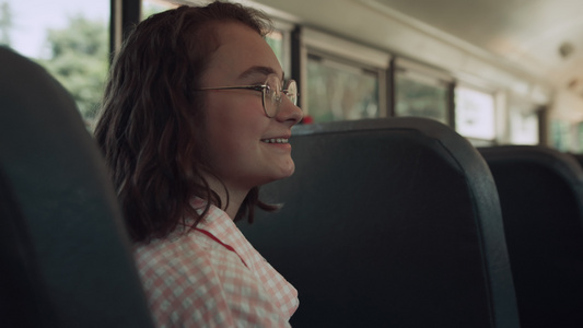 微笑的少女坐在校车上和朋友聊天视频