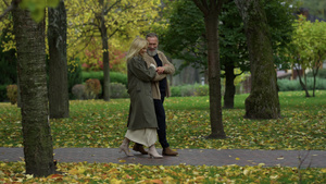 美丽快乐的夫妇在秋天树间行走的侧面镜头23秒视频