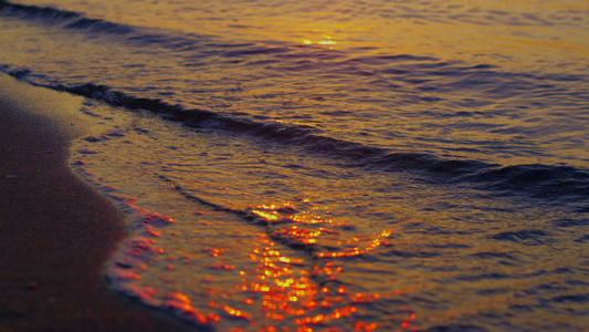 温暖的海水在金色的夕阳傍晚飞溅在黑暗的沙滩上视频