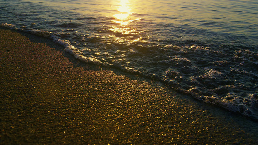 金色日出时海浪溅起沙滩沙子的太阳光反射视频