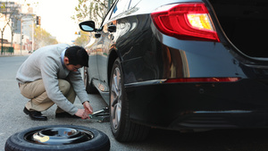 男人在路边使用千斤顶更换汽车备胎39秒视频