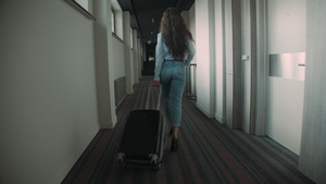 年轻女子在旅馆走廊上拉着行李箱21秒视频