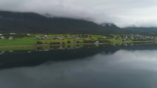 小镇和湖中的倒影夏日多云的挪威绿色景观鸟瞰图无人机视频