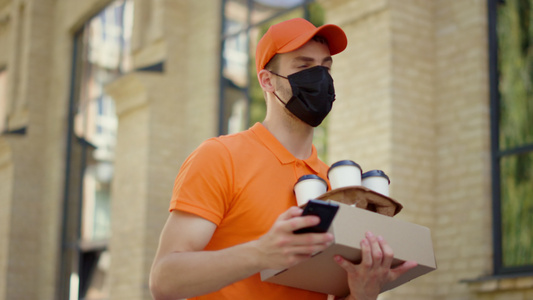 外面使用智能手机的面具信使 送货员在户外订视频