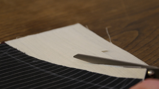 在工作室的桌子上用剪刀剪裁织物剪裁过程的特写特写裁缝视频