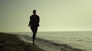 剪影女人在日落时分在海滩上跑步23秒视频