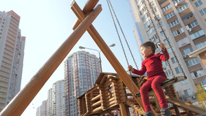 红西装男孩在木摇摆上挥杆童年快乐概念幼儿园背景28秒视频