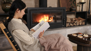 冬季壁炉旁取暖看书的年轻女性26秒视频