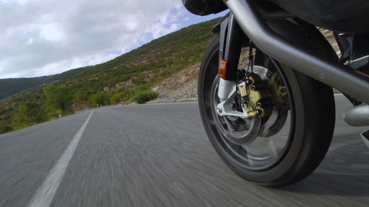 在自然的道路上骑摩托车关闭一个颠簸的沥青路的车轮加速视频