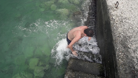 帅帅帅帅的男孩从港口楼梯上的海水里出来慢动作视频