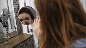年轻女子用放大浴室镜镜检查脸部23秒视频