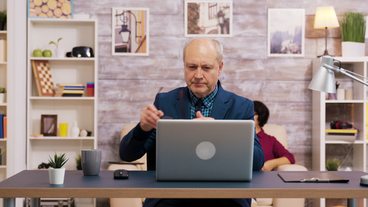 英俊的老人在笔记本电脑工作时戴上眼镜视频