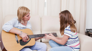 女儿向母亲展示如何在吉他上演奏一首歌11秒视频