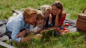 家庭在野餐躺在绿草上看平板电脑28秒视频