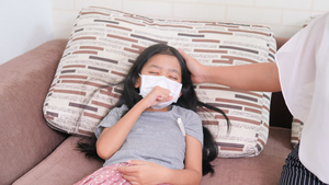 亚洲小女孩戴着外科口罩咳嗽着病倒在沙发上妇女使用儿童9秒视频
