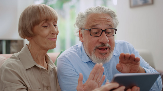 快乐的老年男女在视频通话中用相机挥手视频