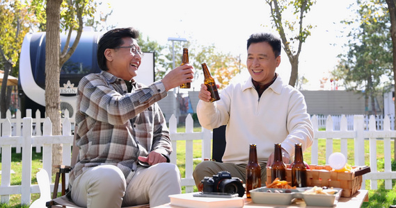两个老年男人坐在房车露营院子里聊天喝啤酒视频