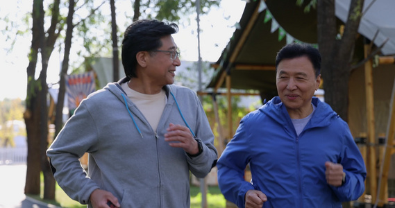 清晨两个中老年男人在露营地林荫道跑步健身视频