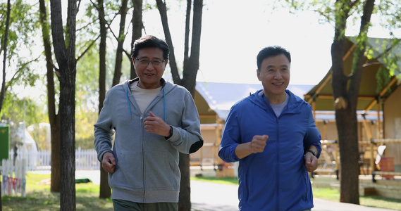 清晨两个中老年男人在露营地林荫道跑步健身视频