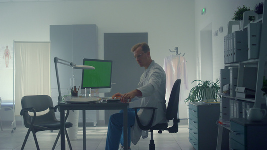 医生坐在办公室工作电脑绿色屏幕视频