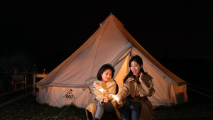 4K升格夜晚闺蜜两人在帐篷前放仙女棒烟花16秒视频