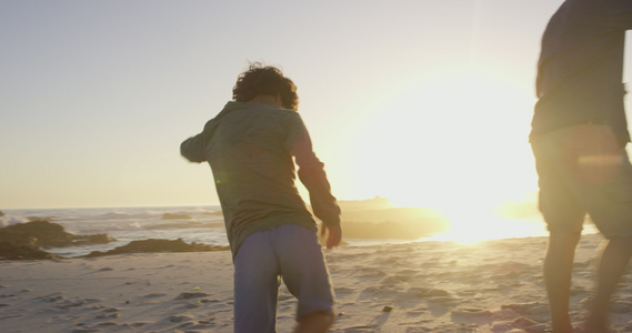 海滩上的父亲和儿子逆光行走在海边视频