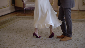 年轻的新婚夫妇在室内跳舞新娘和新郎的腿在地板上穿着6秒视频