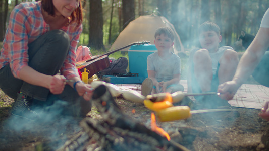 两位母亲在夏季家庭野营度假期间在森林里的帐篷里煮香肠视频