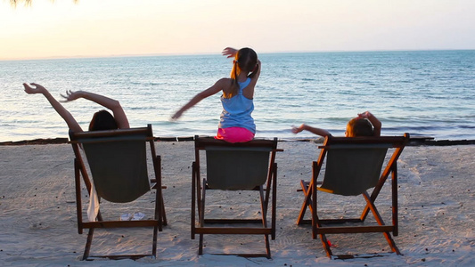 日落时女孩和母亲坐在海滩椅上视频