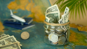 旅行预算概念在世界地图背景的玻璃罐中为假期节省的钱11秒视频