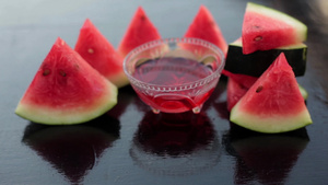 在透明的玻璃杯中与三角面的西瓜一块一起收集西瓜糖浆8秒视频