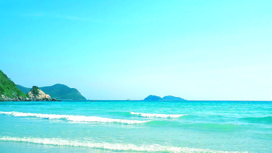 风吹向海滩绿岛和清空天空背景的海浪视频