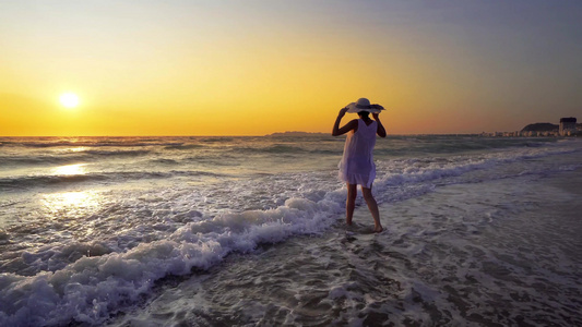 穿着白衣服的年轻姑娘在日落的海滩上独自行走视频