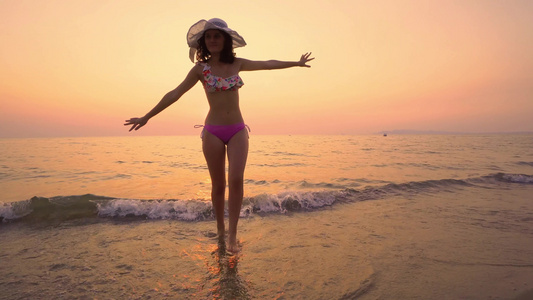 穿着帽子享受美丽日落的帽子在海滩上从水中走出来走出视频